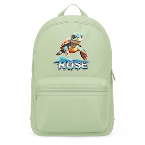 Könnte beinhalten: Hellgrüner Rucksack mit einem farbenfrohen Meeresschildkröten-Design und dem Namen "ROSE" in Blau und Weiß. Die Schildkröte hat einen blau-orangen Panzer und schwimmt in blauem Wasser. Der Rucksack hat eine Vordertasche und einen oberen Griff.