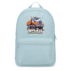 May include: Light blue backpack featuring a colorful illustration of an orange and yellow dump truck with the name "NOAH" in a brown font. The backpack has a large main compartment and a front pocket.