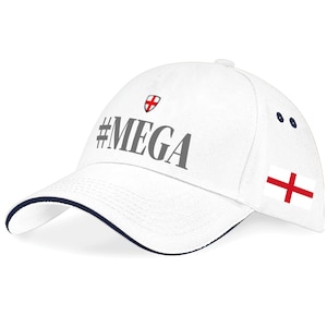 May include: White baseball cap with a navy blue trim. The cap displays the text "#MEGA" in grey, a small shield with a red cross, and the English flag. A classic sports cap.