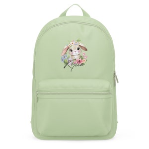 May include: A light green canvas backpack with a cute bunny wearing a flower crown. The bunny is surrounded by flowers and the name "Kylie" is written below it.