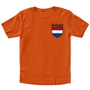 Pode incluir: Camiseta laranja com um pequeno patch bordado com a bandeira holandesa e a palavra "Pa&iacute;ses Baixos" acima.