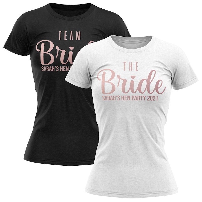 K&ouml;nnte beinhalten: Zwei wei&szlig;e und schwarze T-Shirts mit ros&eacute;goldener Schrift. Das wei&szlig;e Shirt sagt "The Bride" mit einem kleinen Herz und "Sarah's Hen Party 2021". Das schwarze Shirt sagt "Team Bride" mit einem kleinen Herz und "Sarah's Hen".