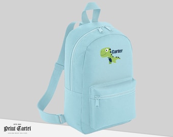 May include: A light blue backpack with a green dinosaur and the name "Carter" embroidered on the front.