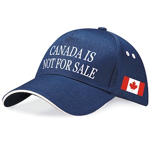 May include: A navy blue baseball cap with the slogan "CANADA IS NOT FOR SALE" in white lettering. The cap has a white trim and a small Canadian flag on the side.