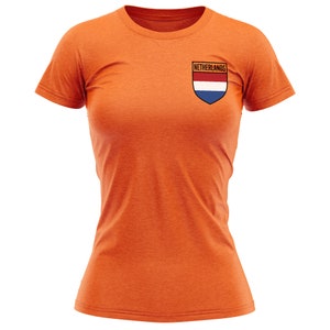 Pode incluir: Camiseta laranja com um pequeno patch no peito esquerdo com a bandeira holandesa e a palavra "Pa&iacute;ses Baixos" acima.
