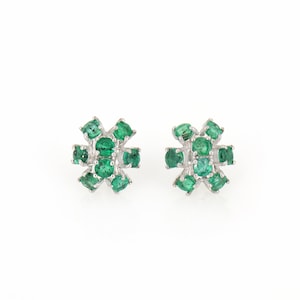 May include: A pair of stud earrings featuring a cluster of vibrant green emeralds set in a silver-toned metal. The emeralds are oval-shaped and arranged in a floral pattern. The earrings are displayed on a white background.