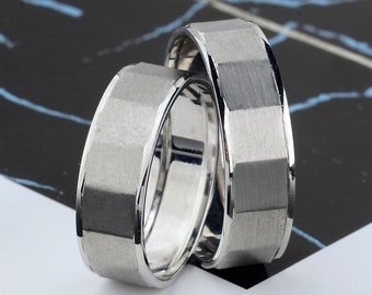 May include: Two silver wedding bands with a brushed finish. The bands are stacked on top of each other.