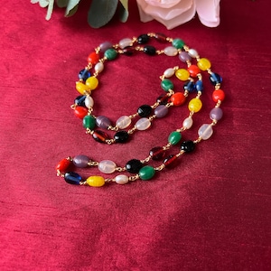 May include: A multi-colored beaded necklace with gold chain links. The beads are oval shaped and include red, yellow, green, blue, purple, black, and white.