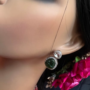 Pu&ograve; includere: Un paio di orecchini d'argento con pietre verdi e trasparenti. Gli orecchini hanno una forma rotonda e sono incastonati con piccole pietre scintillanti.