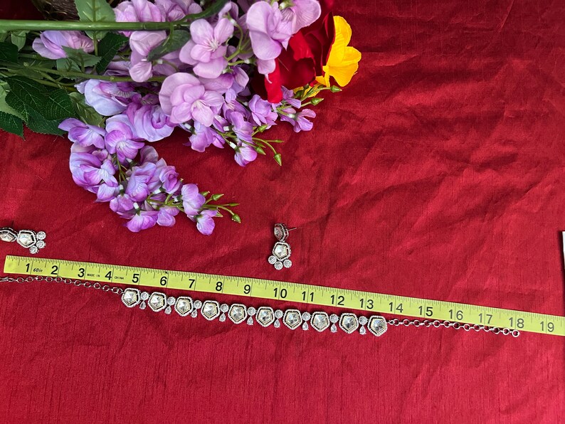 May include: A silver necklace with clear crystal stones and matching earrings. The necklace is 19 inches long and features a delicate chain with a row of hexagonal stones. The earrings are small and dangle from silver hooks.