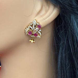 May include: Gold tone earrings with a floral design and pink stones.