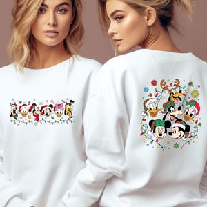 May include: White sweatshirt featuring a festive design with cartoon characters. The front displays a string of characters with Christmas lights, while the back showcases a group of characters in Santa hats and festive decorations. A cozy and cheerful holiday apparel.