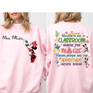 May include: Pink sweatshirt with a Mickey Mouse design on the front and a Disney-themed design on the back. The front design features Mickey Mouse painting the words 'Mrs. Miller.' The back design features a colorful castle, Mickey Mouse, Minnie Mouse, Donald Duck, Goofy, and Tinkerbell. The text on the back reads 'Welcome to our Classroom where the Magic Never Stops and the Adventure Never Ends!'