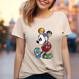 May include: A beige t-shirt with a colorful Mickey Mouse graphic. The graphic is made up of different Disney characters and icons.