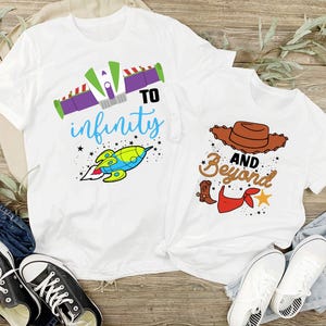 Peut inclure: Deux t-shirts blancs sur le th&egrave;me de Toy Story. Le plus grand t-shirt a une fus&eacute;e et le texte "To infinity". Le plus petit t-shirt a un chapeau de cowboy et le texte "And beyond".