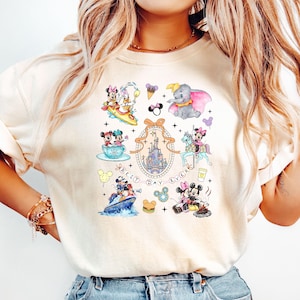 May include: A white t-shirt with a colorful graphic print of various Disney characters, including Mickey Mouse, Minnie Mouse, Donald Duck, and Dumbo. The graphic also includes the text "Best Day Ever" and a depiction of Cinderella's castle.