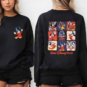 Puede incluir: Sudadera negra con una ilustraci&oacute;n de Mickey Mouse en la parte delantera y una ilustraci&oacute;n de Mickey Mouse de varios paneles en la parte trasera. La ilustraci&oacute;n de la parte trasera incluye el texto "Walt Disney World".