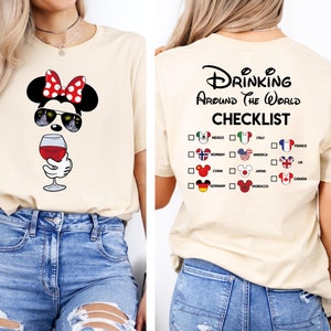 Puede incluir: Una camiseta beige con un gr&aacute;fico de un rat&oacute;n de dibujos animados con gafas de sol y sosteniendo una copa de vino. La parte posterior de la camiseta tiene el texto "Drinking Around the World Checklist" con una lista de pa&iacute;ses y banderas.