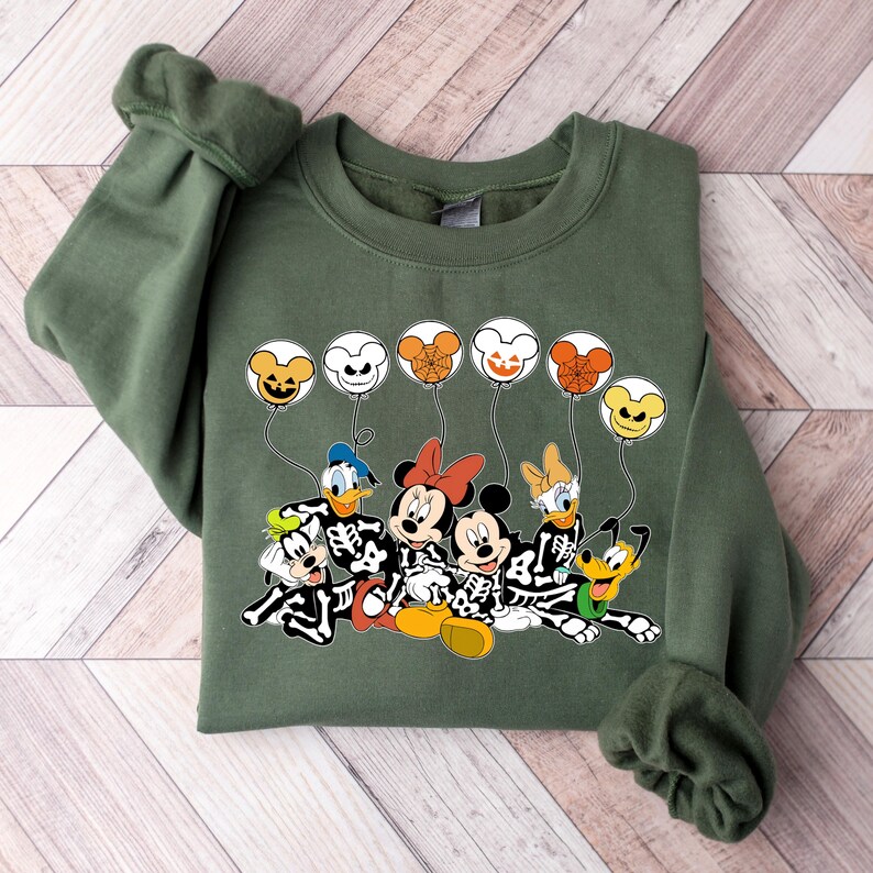 May include: Green sweatshirt with a Halloween-themed design featuring Mickey Mouse, Minnie Mouse, Donald Duck, Goofy, and Pluto dressed as skeletons holding balloons with jack-o'-lantern faces.
