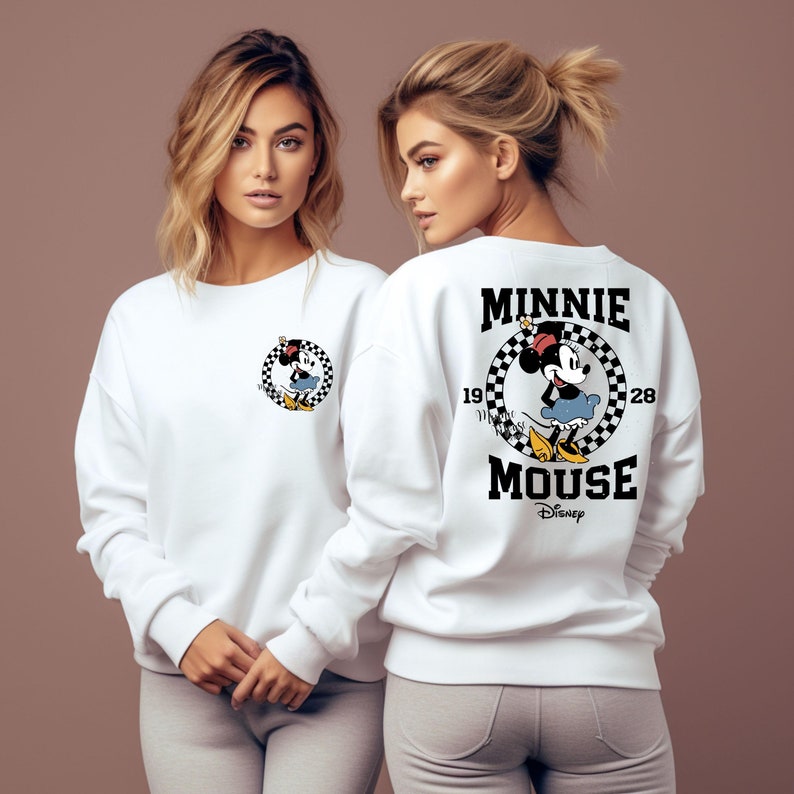 May include: White sweatshirt with a black and white checkered circle graphic featuring Minnie Mouse. The text "Minnie Mouse" is printed in black with a Disney logo below.