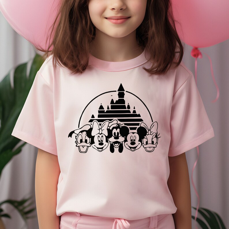 May include: A pink t-shirt with a black graphic of Mickey Mouse, Minnie Mouse, Donald Duck, and Goofy in front of Cinderella's Castle. The graphic is in a circle with a black background.