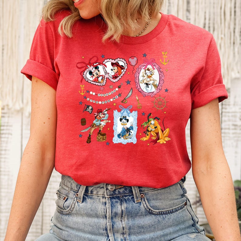 May include: Red t-shirt with a colorful graphic print featuring Mickey Mouse, Minnie Mouse, Donald Duck, Goofy, and other Disney characters. The graphic includes hearts, stars, anchors, and other nautical elements.