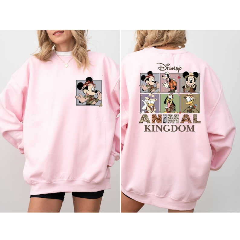 Pu&ograve; includere: Felpa rosa con una grafica di Topolino e altri personaggi Disney in abiti da safari. Il testo "Disney Animal Kingdom" &egrave; stampato sul retro.