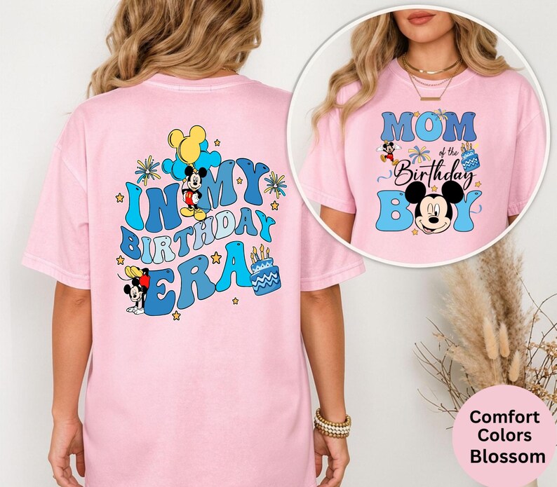 Op de afbeelding: Lichtroze t-shirt met de tekst "IN MY BIRTHDAY ERA" in blauw, met Mickey Mouse-afbeeldingen. De voorkant van het shirt heeft de tekst "MOM of the Birthday Boy" met Mickey Mouse-afbeeldingen. Onderdeel van de Comfort Colors Blossom collectie.
