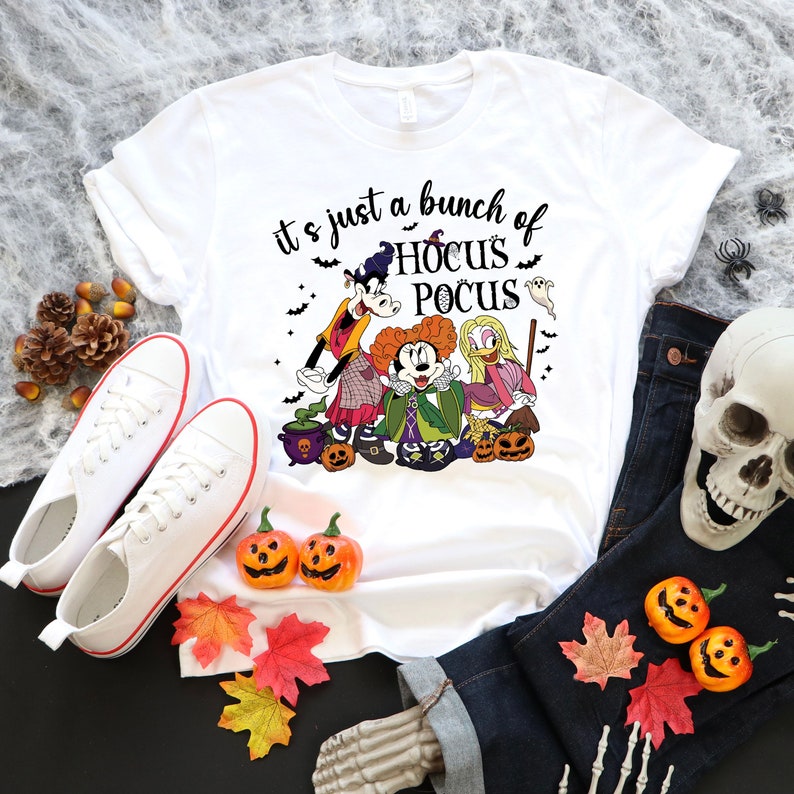 Op de afbeelding: Wit T-shirt met een afbeelding van Mickey Mouse, Goofy en Winifred Sanderson uit de film Hocus Pocus. De tekst "it's just a bunch of Hocus Pocus" staat op het T-shirt gedrukt.