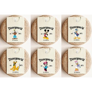 May include: Six cream-colored t-shirts featuring Disney characters like Goofy, Mickey Mouse, Donald Duck, Pluto, Minnie Mouse, and Daisy Duck. Each shirt has the "Disneyworld" logo, "est. 1971," and "FLORIDA" printed in black.