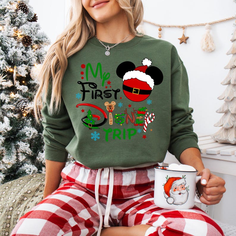 May include: Green Christmas themed sweatshirt with the text "My First Disney Trip" and a Mickey Mouse head wearing a Santa hat.