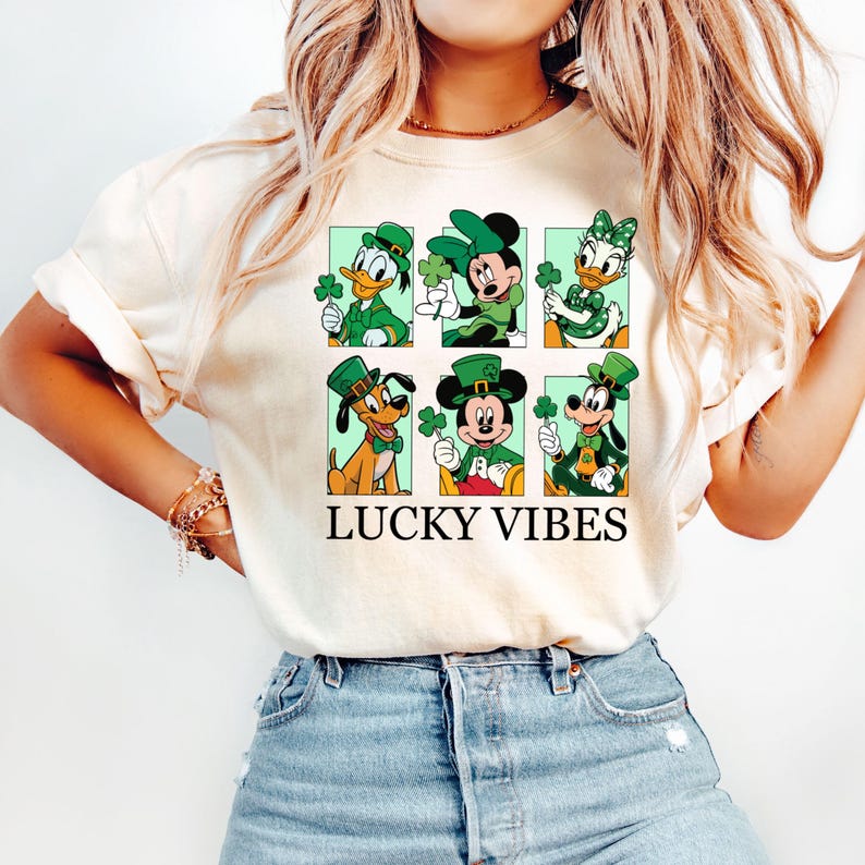May include: A white t-shirt with a graphic of Mickey Mouse, Minnie Mouse, Donald Duck, and Goofy wearing green hats and holding shamrocks. The text "LUCKY VIBES" is printed below the graphic.