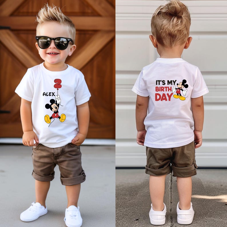 Puede incluir: Camiseta blanca con un gr&aacute;fico de Mickey Mouse y el texto "It's My Birthday" en la parte posterior. La parte delantera de la camiseta tiene un gr&aacute;fico de Mickey Mouse y el texto "Alex" con un globo n&uacute;mero 2.