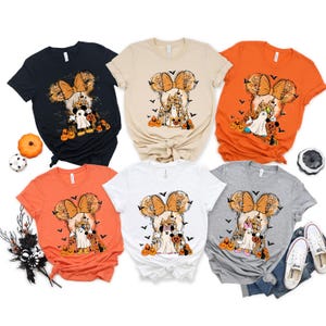 May include: Six different colored t-shirts with a Halloween-themed Mickey Mouse design. The shirts are in black, beige, orange, white, and gray.