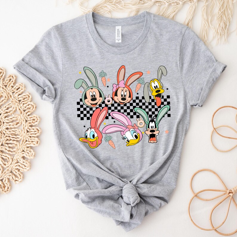 May include: A gray t-shirt with a checkered pattern and a graphic of cartoon characters with bunny ears. The characters include Mickey Mouse, Minnie Mouse, Donald Duck, Goofy, and Pluto.