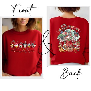 Op de afbeelding: Rode sweatshirt met Disney-personages in kerstoutfits. De voorkant toont een rij personages met kerstverlichting, terwijl de achterkant een groter ontwerp toont met de tekst "Walt Disney World" en meer personages.