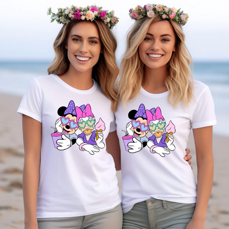 Pode incluir: Duas camisetas brancas com uma estampa gr&aacute;fica de Minnie Mouse e Daisy Duck usando &oacute;culos de sol em forma de cora&ccedil;&atilde;o e segurando cones de sorvete. O gr&aacute;fico &eacute; em rosa, roxo, azul e amarelo.