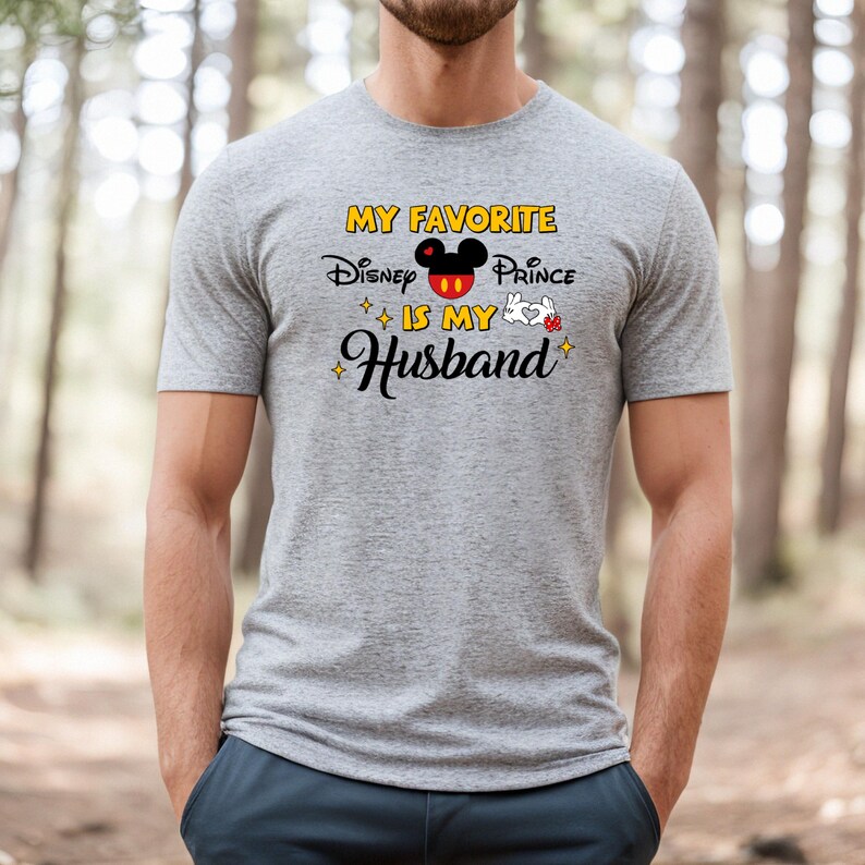 May include: A gray t-shirt with the text "MY FAVORITE Disney Prince IS MY Husband" in yellow, black, red, and white. The design includes a Mickey Mouse head and white gloves.
