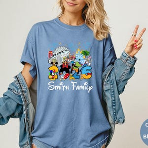 May include: Blue t-shirt featuring Disney characters and the number "2026" with "Smith Family" in white script. The design includes Mickey Mouse, Donald Duck, and other characters in a colorful illustration.