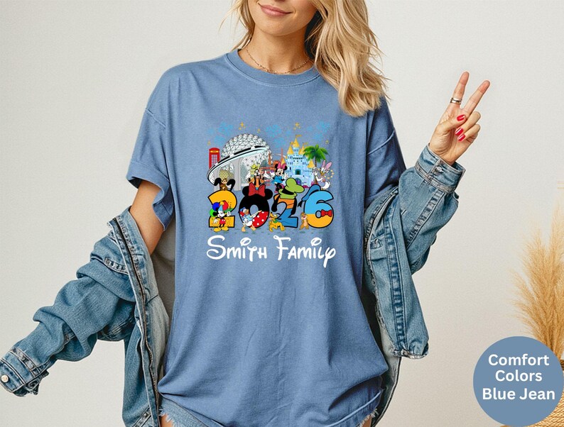 May include: Blue t-shirt featuring Disney characters and the number "2026" with "Smith Family" in white script. The design includes Mickey Mouse, Donald Duck, and other characters in a colorful illustration.