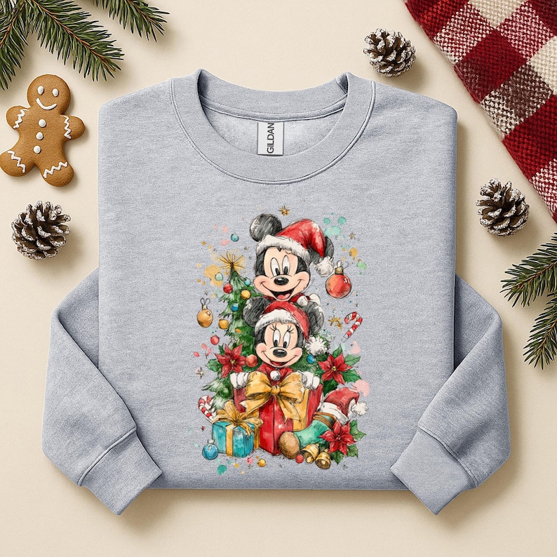 May include: A light gray sweatshirt featuring a festive Christmas design with Mickey and Minnie Mouse wearing Santa hats. The graphic includes a Christmas tree, presents, and candy canes, perfect for holiday wear.