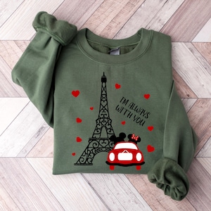 May include: Green sweatshirt with a black and white graphic of the Eiffel Tower, a red car, and two cartoon figures. The text "I'm always with you" is printed on the sweatshirt.