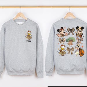 May include: A gray sweatshirt with a cartoon image of Donald Duck and Mickey Mouse on the back. The front of the sweatshirt has a cartoon image of Donald Duck and the name "Paul" printed on it.
