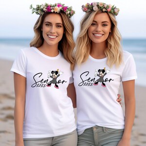 May include: Two white t-shirts with a black and white graphic of a cartoon mouse wearing a graduation cap and gown. The text "Senior 2023" is on the left shirt and "Senior 2023" is on the right shirt.
