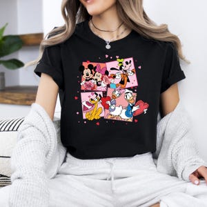 May include: Black t-shirt with a graphic print of Mickey Mouse, Minnie Mouse, Donald Duck, Goofy, and Pluto holding Valentine's Day hearts. The characters are surrounded by pink hearts.