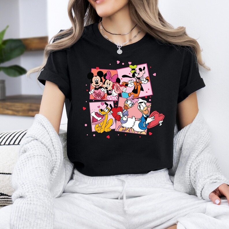May include: Black t-shirt with a graphic print of Mickey Mouse, Minnie Mouse, Donald Duck, Goofy, and Pluto holding Valentine's Day hearts. The characters are surrounded by pink hearts.