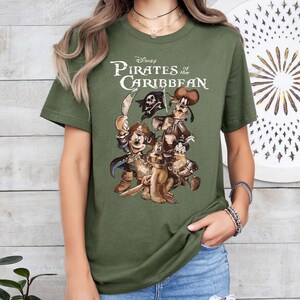 Pode incluir: Camiseta verde com uma estampa gr&aacute;fica de Mickey Mouse, Pateta e Donald Duck vestidos de piratas. O texto "Disney Pirates of the Caribbean" est&aacute; impresso acima dos personagens.