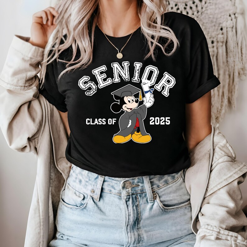 K&ouml;nnte beinhalten: Schwarzes T-Shirt mit einem wei&szlig;en Aufdruck von Mickey Mouse, der eine Graduation Cap tr&auml;gt und ein Diplom h&auml;lt. Der Text "Senior Class of 2025" ist auf dem Shirt aufgedruckt.