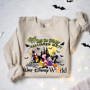 May include: A beige sweatshirt with a graphic print of Mickey Mouse and friends in a Halloween setting. The text reads "Mickey's Not So Scary Halloween Party Walt Disney World".