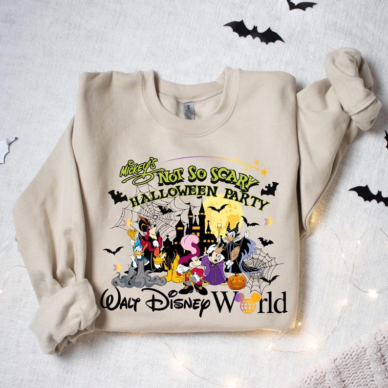 May include: A beige sweatshirt with a graphic print of Mickey Mouse and friends in a Halloween setting. The text reads "Mickey's Not So Scary Halloween Party Walt Disney World".